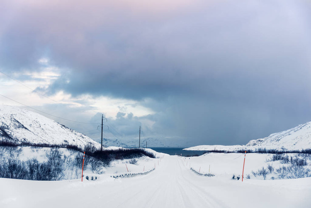 Snow covered winter road leads to the sea: a gulf or fjord surrounded by mountains in the far North above the Arctic Circle - Foto, Imagem