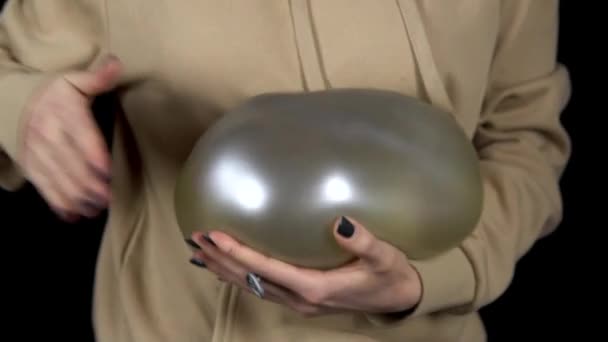 Μια νεαρή γυναίκα χτυπάει ένα μπαλόνι με νερό. Η μπάλα τρέμει από τα χτυπήματα. Γυναίκα κρατά μια μπάλα με vodo στα χέρια της σε ένα μαύρο φόντο closeup. Αργή κίνηση - Πλάνα, βίντεο