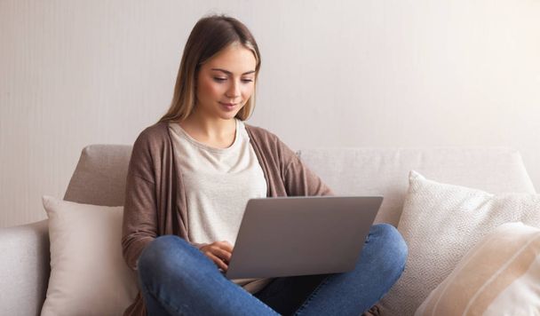 Encantadora chica millennial escribiendo en el ordenador portátil en casa
 - Foto, imagen