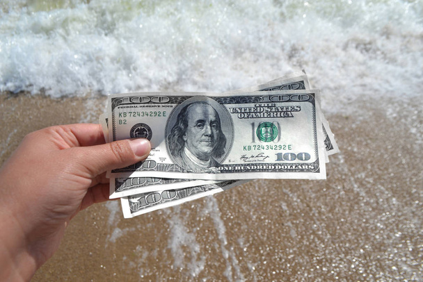 Κορίτσι που κατέχουν χρήματα νομοσχέδιο των 300 δολαρίων στο φόντο των ωκεανών της θάλασσας - Φωτογραφία, εικόνα