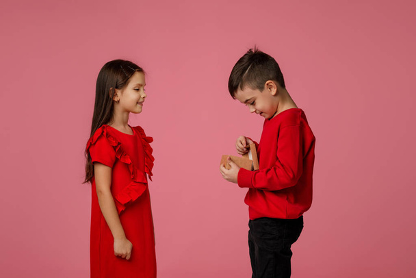 Happy little child boy gives smiling girl a gift box - Photo, Image