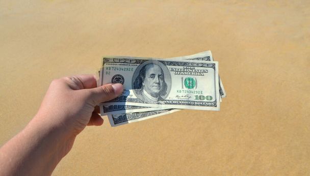Κορίτσι που κατέχουν χρήματα νομοσχέδιο των 300 δολαρίων στο φόντο της θάλασσας ωκεανό - Φωτογραφία, εικόνα