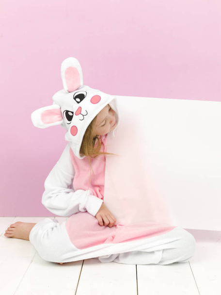 happy pretty blonde girl in cozy rabbit costume with white sign posing in studio  - Foto, Bild
