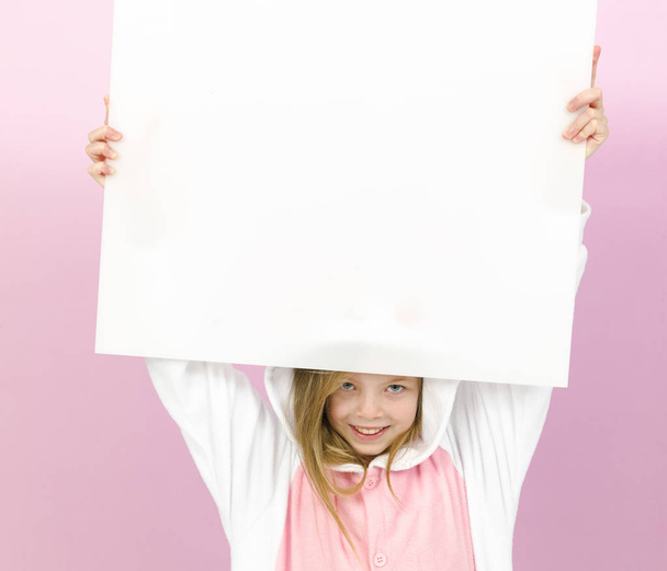happy pretty blonde girl in cozy rabbit costume with white sign posing in studio  - Foto, Imagem
