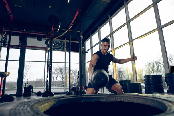 The male athlete training hard in the gym. Fitness and healthy life concept. - Fotoğraf, Görsel