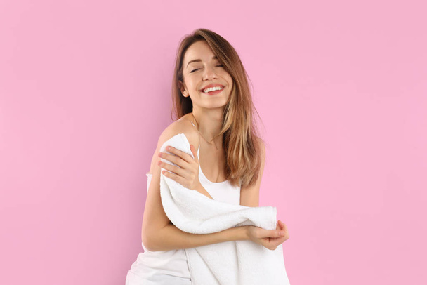 Young woman wiping body with towel on light pink background - Valokuva, kuva