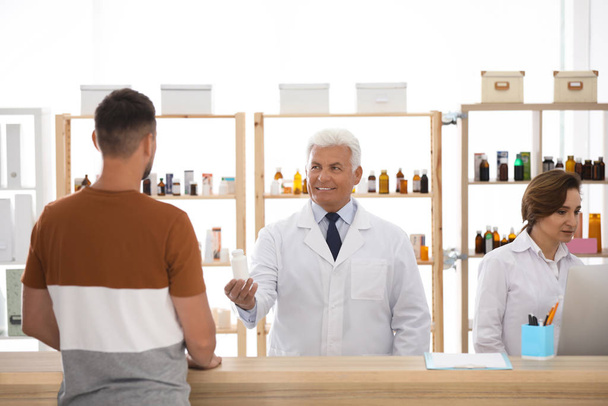 Pharmacist giving medicine to customer in drugstore - Fotoğraf, Görsel