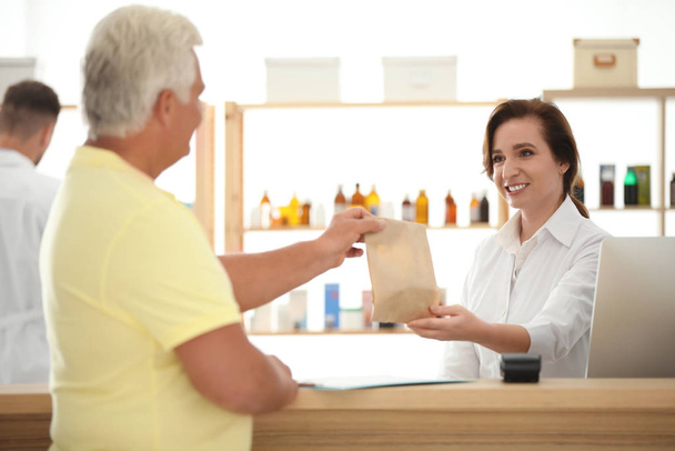 Pharmacien donnant des médicaments au client en pharmacie
 - Photo, image