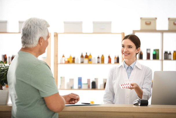 Pharmacist giving medicine to customer in drugstore - Foto, imagen
