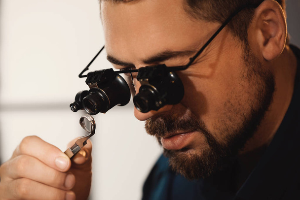 Jeweler working with ring on blurred background, closeup - 写真・画像