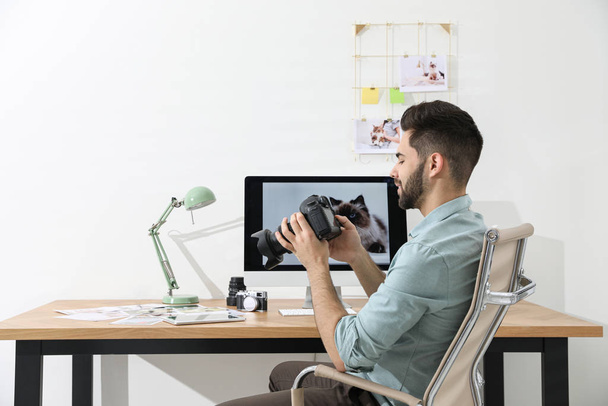 Professional photographer with camera working at table in office - Foto, Imagen