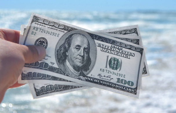 Meisje met geld rekening van 300 dollar op de achtergrond van de zee oceaan - Foto, afbeelding