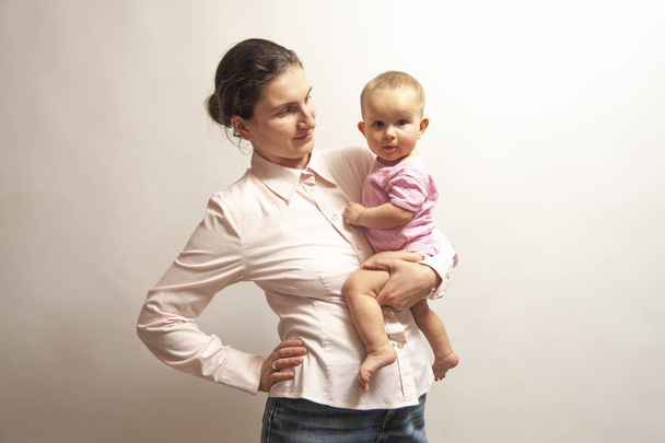 Infant baby girl with mum in a light pink shirt a white background isolated. - Foto, imagen