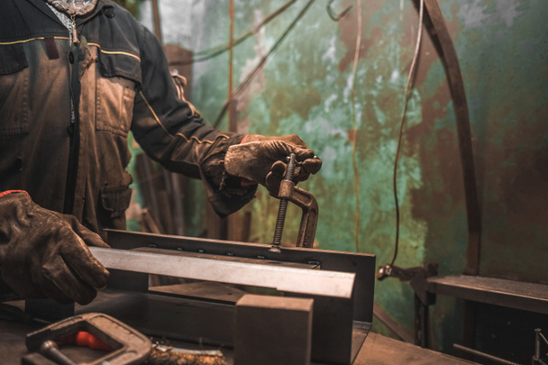 Man klemmt Eisenprodukte in C-Klemmen. Mann arbeitet mit Werkstattkonzept clamps.steel - Foto, Bild