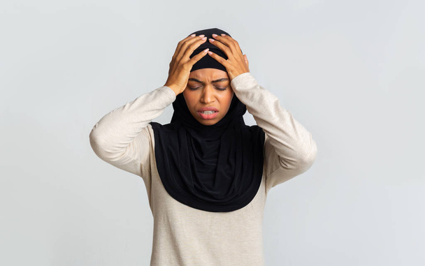 Sick black muslim lady in headscarf touching her head with hands - Photo, Image
