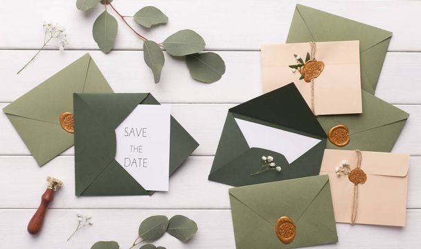 Stylish dark green envelopes with accessories on white - Foto, imagen