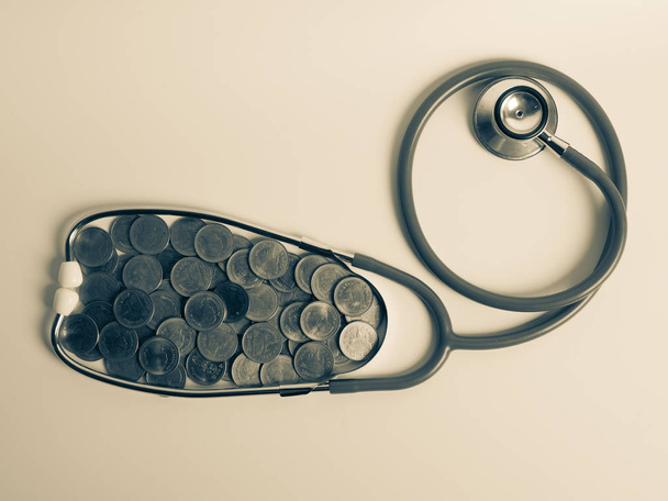 Медицинский стетоскоп и стопка монет изолированы на белом фоне
 - Фото, изображение