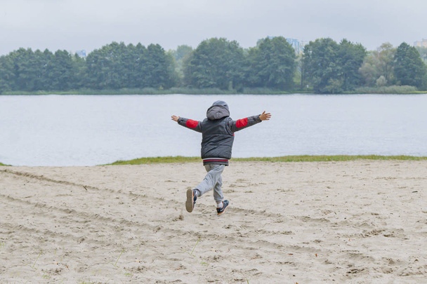 A little boy walks alone on the river Bank in autumn - Foto, Imagem