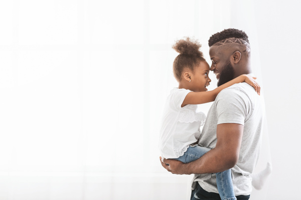 Loving african father carrying his preschool daughter over white background - Foto, Imagem