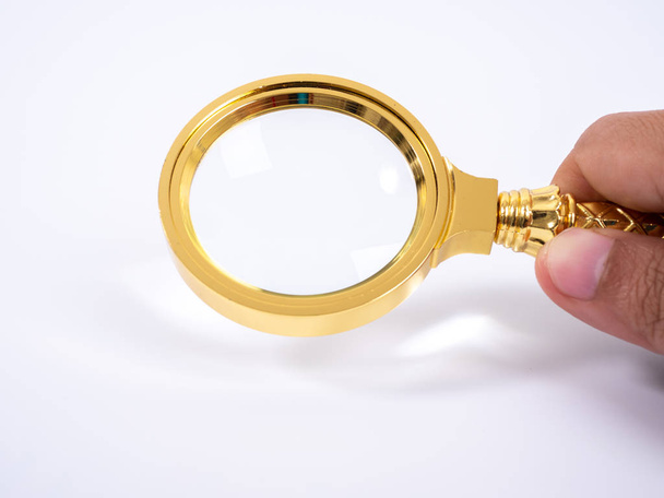 Golden magnifying glass in hand on white background - Photo, Image