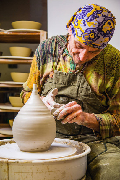 Potter working on potter's wheel with raw clay with hands, making new amphora bowl, small art business concept - Photo, Image