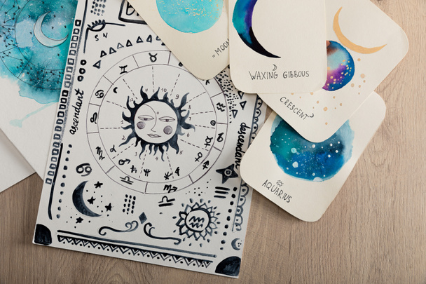 Top view of birth chart and cards with zodiac signs on wooden table - Photo, Image