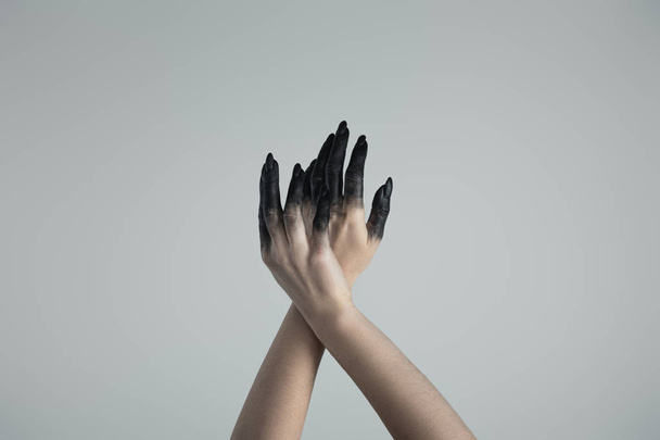 Cropped view of witch hands in black paint isolated on grey - Foto, afbeelding