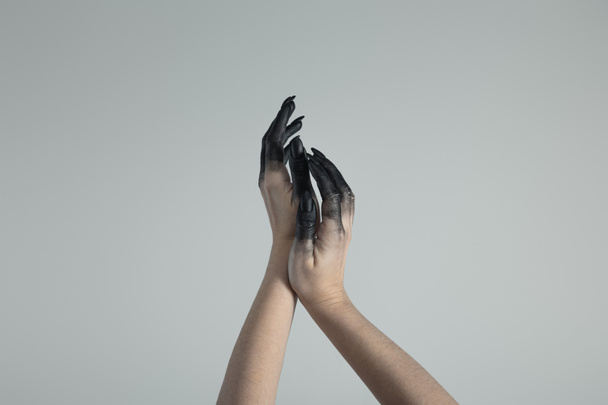 Καλλιεργημένη άποψη των χεριών μάγισσα σε μαύρο χρώμα απομονώνονται σε γκρι  - Φωτογραφία, εικόνα