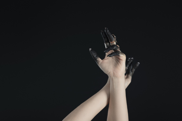 Cropped view of hands of witch with jewelry rings and black painted fingers isolated on black  - Foto, Imagem