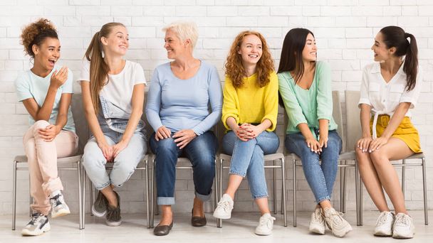 Mulheres alegres e diversas conversando sentadas em cadeiras internas, Panorama
 - Foto, Imagem