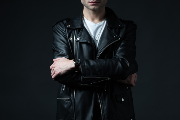 cropped view of stylish brutal man in biker jacket with crossed arms isolated on black - Фото, изображение