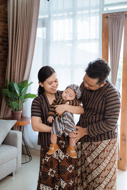 father and mother wearing javanese batik looking at sleepy cute little son - 写真・画像