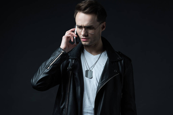 tense stylish man talking on smartphone isolated on black - Fotografie, Obrázek