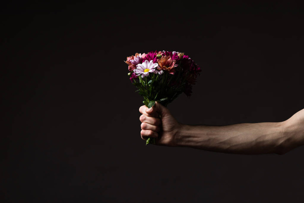 cropped view of man holding floral bouquet isolated on black - Fotoğraf, Görsel