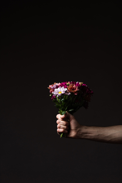 cropped view of man holding floral bouquet isolated on black - Valokuva, kuva