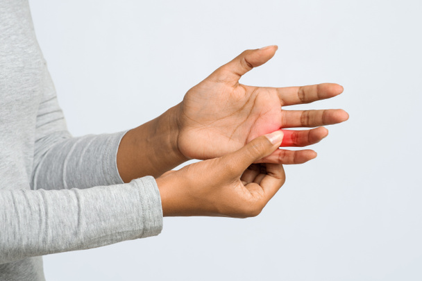 Молодая женщина массирует свой болезненный палец, обрезает
 - Фото, изображение