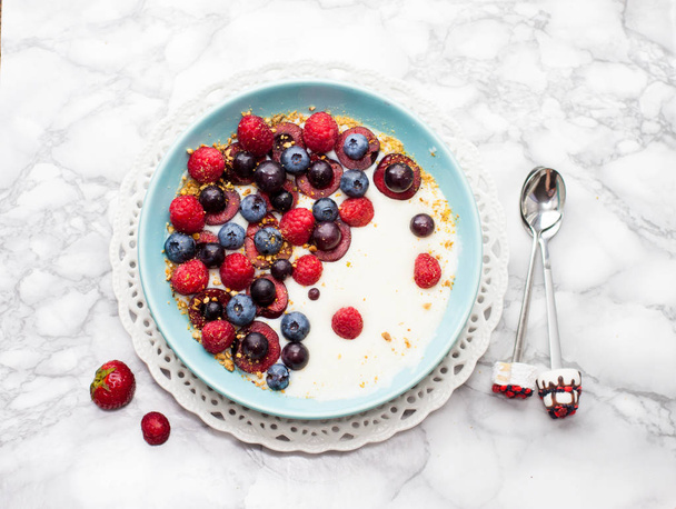 Blue bowl with oatmeal, fresh strawberries, cherries, raspberries and blueberries.  - Foto, afbeelding