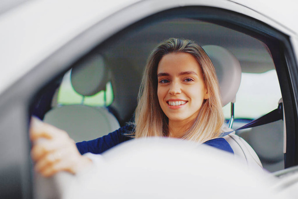 Young blonde woman in her new car smiling. - Photo, image