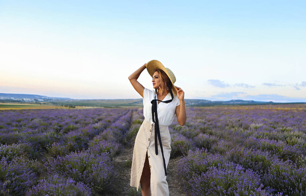 Beautiful woman in straw hat in violet lavender field  - Фото, изображение