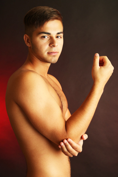Young man with hand pain on dark background - Valokuva, kuva