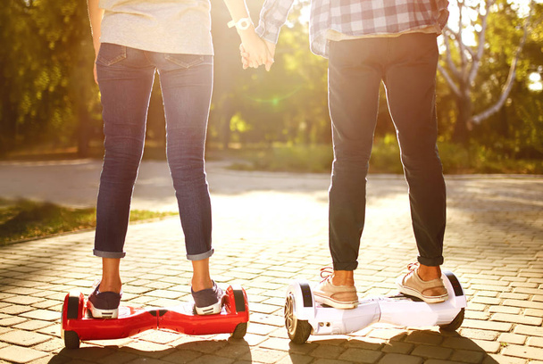 Nohy muže a ženy jezdí na vznášedle pro relaxační čas spolu venku ve městě. Mladý pár jedoucí na vznášedle v parku, samovyvažující skútr. Budoucnost technologie aktivního životního stylu. - Fotografie, Obrázek