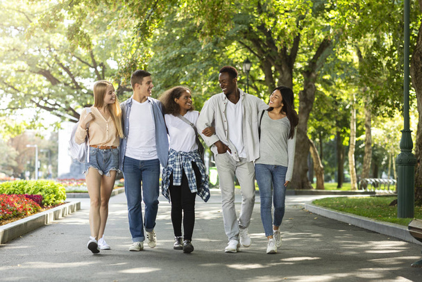 Estudiantes felices caminando juntos en el parque público después de estudiar
 - Foto, imagen