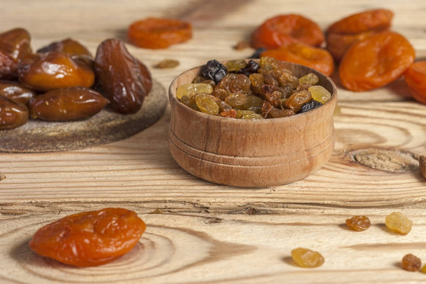 Maukkaita rusinoita, päivämääriä ja kuivattuja aprikooseja puupöydällä
 - Valokuva, kuva