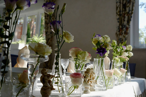 Restorandaki düğün masasında güzel bir çiçek aranjmanı, fotokopi odası. Bir buket pembe gül, mor Eustoma ve cam vazolarda yeşillik. - Fotoğraf, Görsel