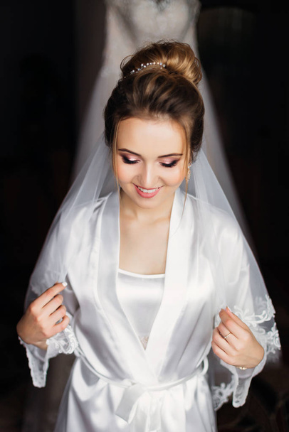 beautiful bride in white bathrobe with make up and bridal veil c - Photo, image