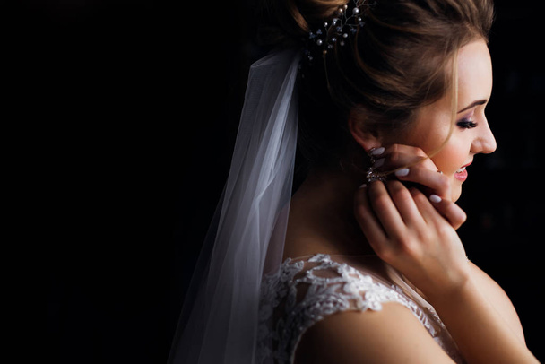 bride of profile with wedding veil and white dress. girl fixes e - Foto, Imagen