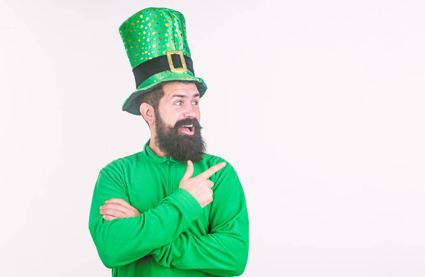 Pointing at something aside. Irish man with beard pointing his finger. Bearded man celebrating saint patricks day. Hipster in green leprechaun hat and costume. Happy saint patricks day, copy space - Photo, Image