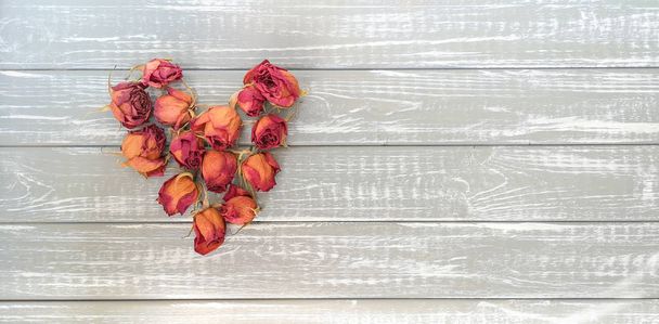 Gedroogde rozen in de vorm van het hart op de achtergrond van houten platen geschilderd in grijs.Concept van het idee van tijdloze liefde.Kopieer ruimte - Foto, afbeelding