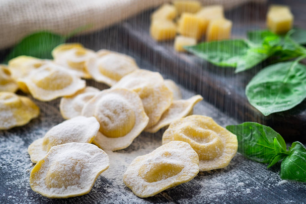 Raw ravioli with cheese and Basil sprinkle flour on wooden backg - Photo, Image