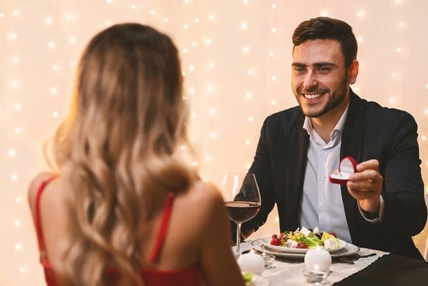 Мужчина просит девушку выйти за него замуж за романтический ужин в ресторане
 - Фото, изображение